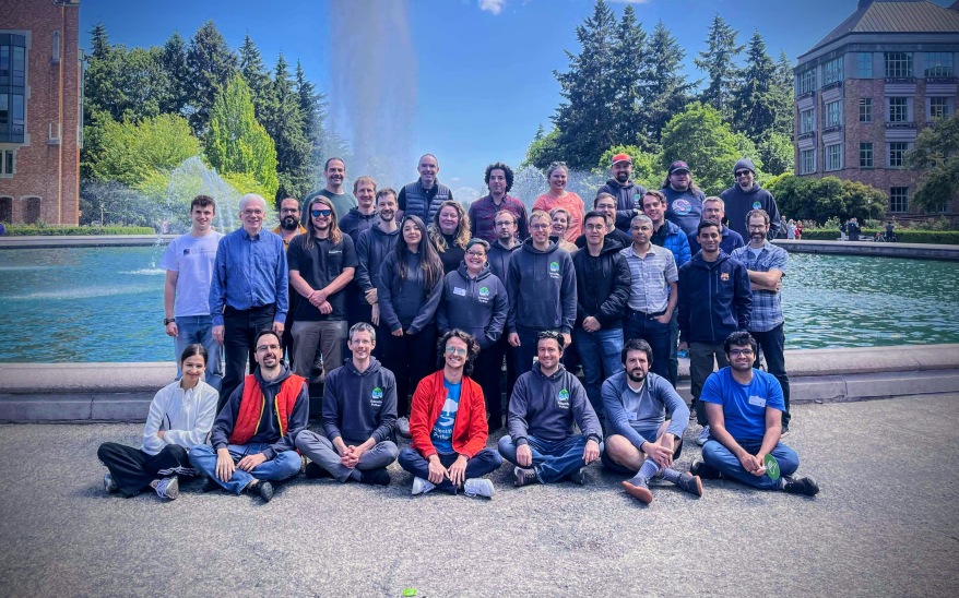 Photo of the summit attendees, in front of a fountain on the University of Washington campus, with a volcano in the background